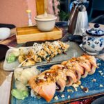 a plate of sushi with chopsticks on a table